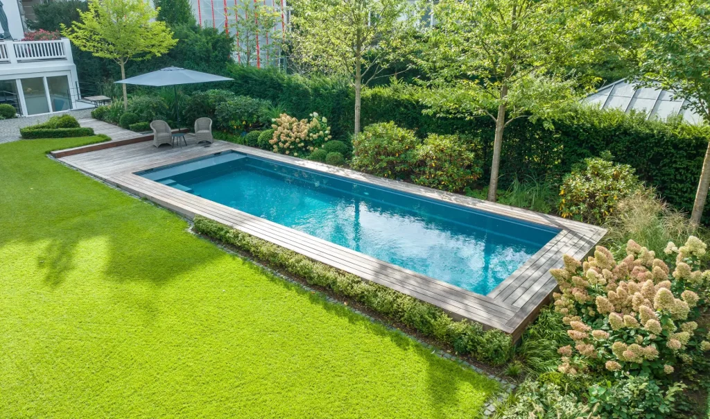 Vgradni bazen Compass Pools na sodobnem vrtu z leseno teraso